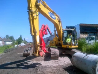 A Clumber Construction excavator and some large diamater black pipes